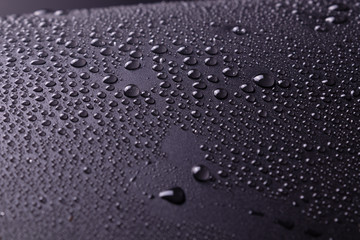 on a dark gray background in a studio with white lighting and unevenly sprayed drops of water and white highlights.