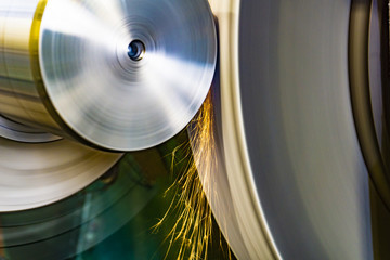 An abrasive wheel performs the grinding of a part on a circular grinding machine with sparks.