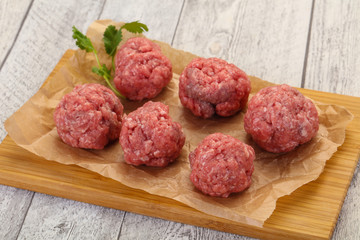 Raw meatball over wooden background