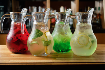 Different soft drinks in transparent jugs on a dark wooden background. menu for catering