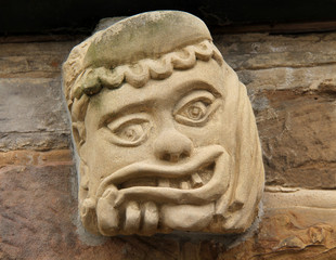 An Ancient Stone Face Gargoyle Mounted on a Wall.