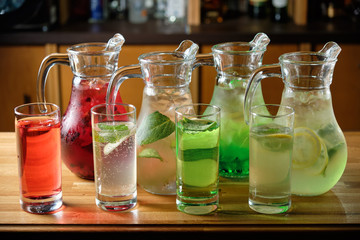 Different soft drinks in transparent jugs on a dark wooden background. menu for catering