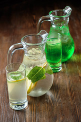 Different soft drinks in transparent jugs on a dark wooden background. menu for catering