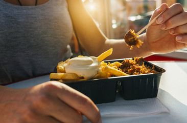 Frau isst Currywurst und Pommes Mayo in Fußgängerzone 
