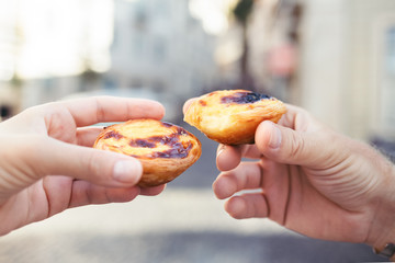 Traditional portuguese desserts in woman's and man's hands. Pastel de Nata.