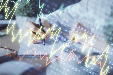 Financial forex graph displayed on hands taking notes background. Concept of research. Double exposure