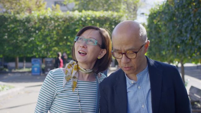 Senior Asian couple in love, walking through a park one day, in slow motion