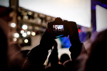 Professional dslr camera at music concert in raised up hand recording singer on a stage.