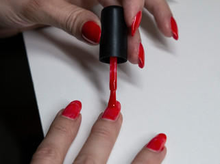 applying red gel nail polish on women's nails