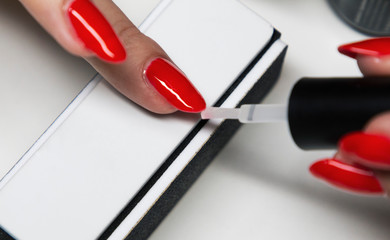 applying red gel nail polish on women's nails