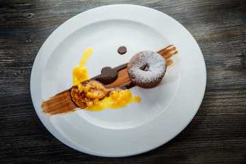 small chocolate cupcake decorated with sugar powder and with fruit syrop