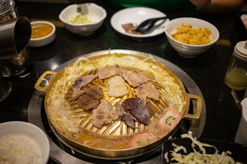 Sliced meats grilling on brass pan in Korean BBQ buffet restaurant