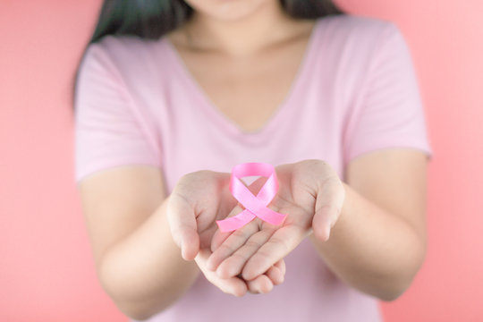 Healthcare, medicine and breast cancer awareness concept. Closeup woman hands holding pink breast cancer awareness ribbon.