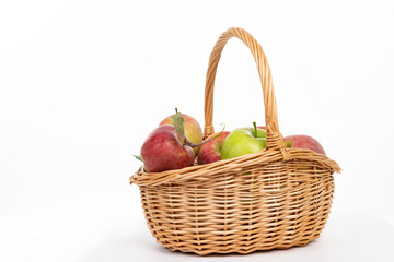 Wicker basket full of fall red and green apples isolated on white