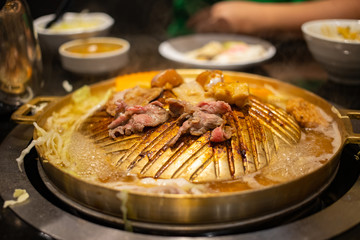 Sliced meats grilling on brass pan in Korean BBQ buffet restaurant