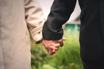 Elderly wife and husband holding hands close up.