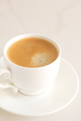 white cup with black coffee on a white marble background