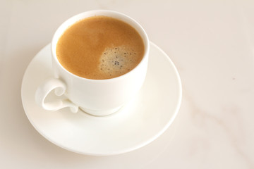 white cup with black coffee on a marble background