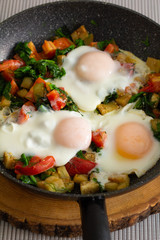 fried eggs with vegetables in a pan