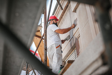 Man worker standing on scaffolding and restore old building facade