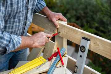 Adult carpenter craftsman with screwdriver screw the screw to fix the boards of a wooden fence. Housework do it yourself. Stock photography.