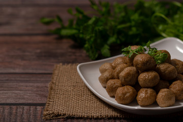Stack of baked meatballs in white dish on wodden background, copy space.