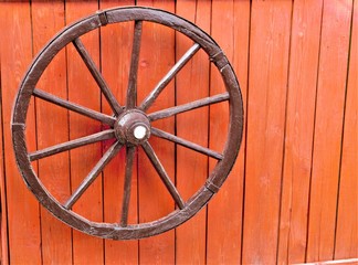 old wooden wheel on red background