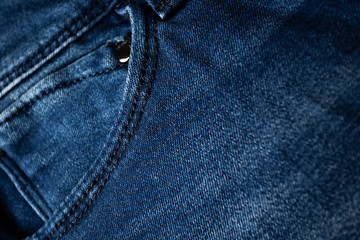 Fototapeta premium Small fifth pocket on blue jeans close-up. Denim, fashion concept. Place for text. Dark blue shades.