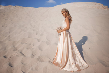 Fototapeta na wymiar Beautiful bride is wearing fashion flying dress and wreath in the great desert in Dubai.