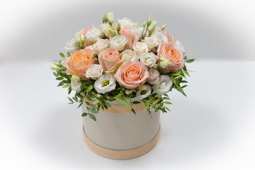 Wonderful flower arrangement in a hat box on a light background (Flowers: Rose, Eustoma. Colors: white, pink, beige)