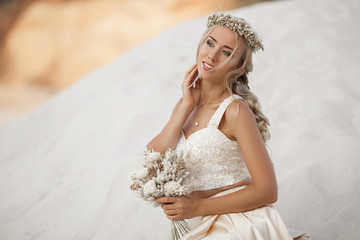 Fototapeta na wymiar Portrait of beautiful bride is wearing fashion flying dress and wreath in the great desert in Dubai.