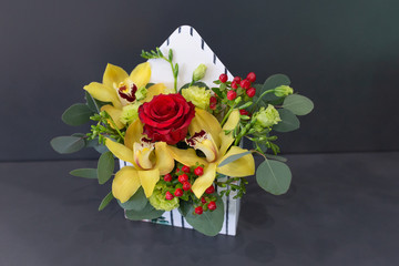 Sensual floral arrangement of exotic flowers in a box - an envelope on a dark background