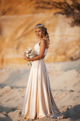 Fototapeta na wymiar Beautiful bride is wearing fashion flying dress and wreath in the great desert in Dubai.