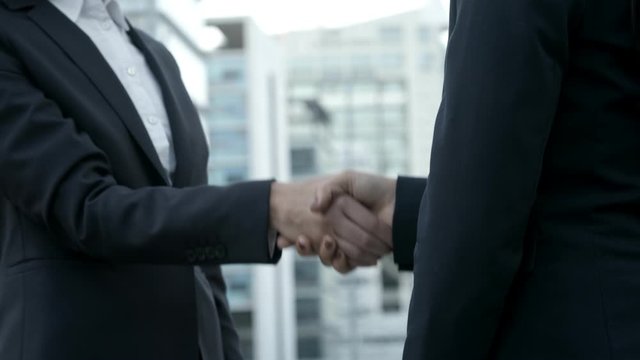 Cropped shot of businesswomen shaking hands on street. Colleagues meeting on street and making handshake. Business handshake concept