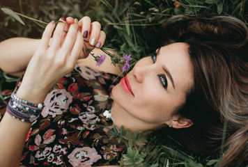 Portrait of beautiful woman with flower in the grass in the field