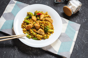 Rice with chicken meat and vegetables in a plate on stone table