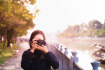 Asian female traveller taking photograph with digital mirrorless camera in Saigon city.