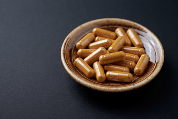 Turmeric capsules. Black background. Close up. Copy space. 