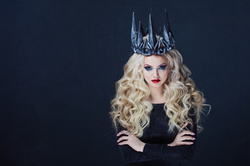 Portrait of a Gothic Queen. Beautiful young blonde woman in metal crown and black cloak.