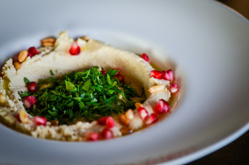 lebanese hummus dish with fresh vegetables, beef meat & pomegranate seeds