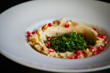 lebanese hummus dish with fresh vegetables, beef meat & pomegranate seeds