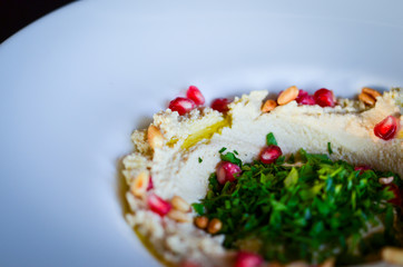 lebanese hummus dish with fresh vegetables, beef meat & pomegranate seeds