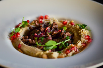 lebanese hummus dish with fresh vegetables, beef meat & pomegranate seeds