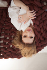 Cute young blonde lying on the bed wrapped in a soft cozy blanket. Warmth and comfort of home