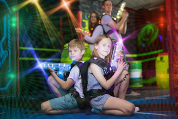 Kids sitting back to back with laser guns in beams