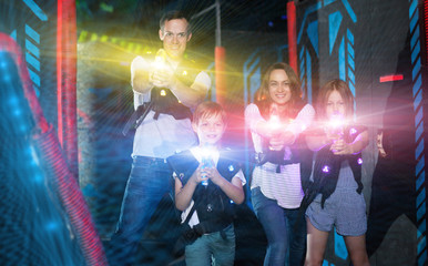 Obraz na płótnie Canvas Kids and parents in beams during laser tag game