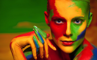 Portrait of the bright beautiful young woman with face art and body art. Contrast colors in...