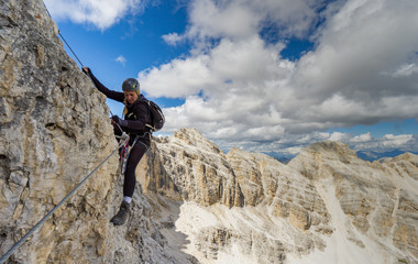 attractive blonde female mountain climber on a steep Via Ferrata in the Italian Dolomites