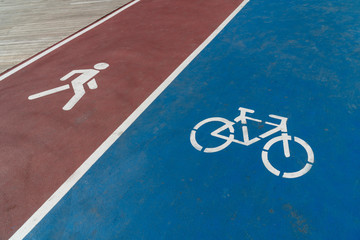 Blue bicycle lane sign and red walking lane sign on road.