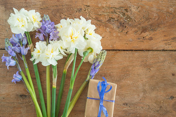 Beautiful bouquet of white daffodils and blue hyacinth flowers, hand made gift box on the vintage wooden background with copy space